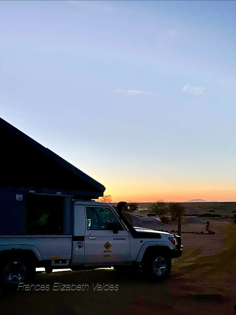 Land cruiser with erect roof top tent and the orange glow of sunset, at Elephant Song Campsite, near Brandberg Mountain, Erongo, Namibia